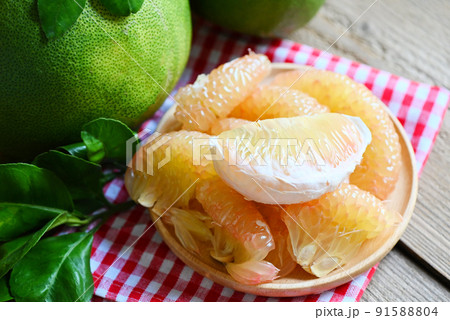 fresh green pomelo peeled and leaf frome pomelo tree , pummelo , grapefruit in summer tropical fruit in thailand , pomelo fruit on wooden plate background fresh green pomelo peeled and leaf frome pomelo tree , pummelo , grapefruit in summer tropical fruit in thailand , pomelo fruit on wooden plate background 91588804