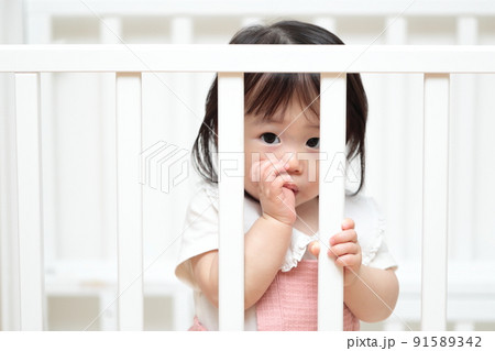 ベビーベッドでおしゃぶりをする1歳の女の子 ベビーベッドでおしゃぶりをする1歳の女の子 91589342