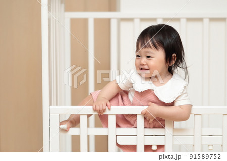 ベビーベッドをよじ登る1歳の女の子 91589752