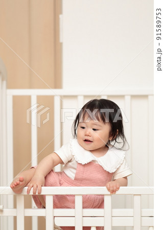 ベビーベッドをよじ登る1歳の女の子 91589753