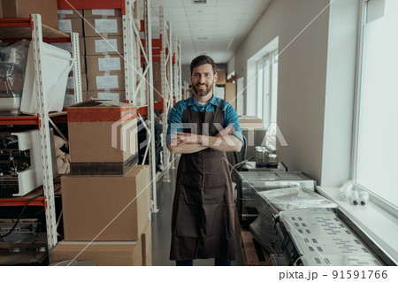 Portrait of rman in uniform standing on workshop of coffee machines warehouse 91591766