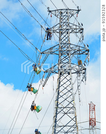 鉄塔と高所で高圧線工事をする作業員 91592328