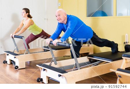 Elderly man press exercises on pilates reformer at studio Elderly man press exercises on pilates reformer at studio 91592744