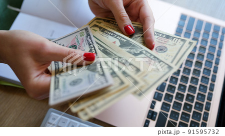 Woman holding cash in hand and counting banknotes Woman holding cash in hand and counting banknotes 91595732