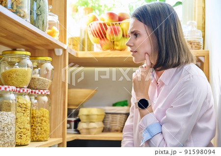 Young woman in kitchen with containers jars of food Young woman in kitchen with containers jars of food 91598094