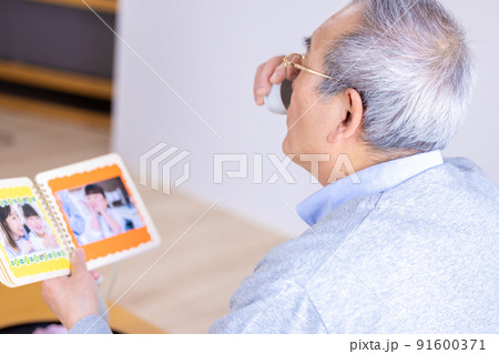 孫の写真を見ながらお酒を飲むおじいちゃん 孫の写真を見ながらお酒を飲むおじいちゃん 91600371