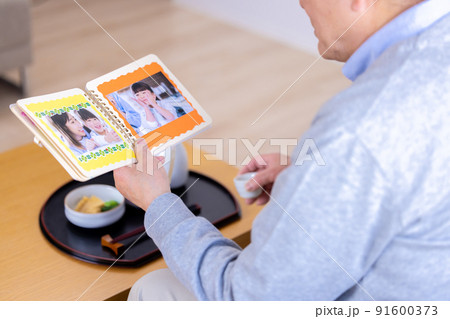孫の写真を見ながらお酒を飲むおじいちゃん 孫の写真を見ながらお酒を飲むおじいちゃん 91600373