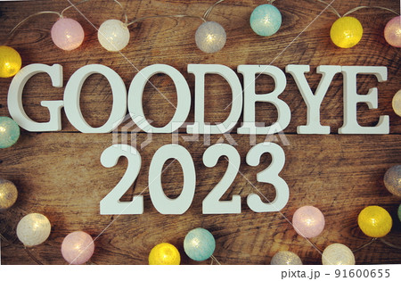 Goodbye 2023 alphabet letters and LED cotton ball decoration on wooden background 91600655
