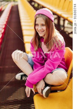 Portrait of a charming girl sitting on the school bleachers during a break Portrait of a charming girl sitting on the school bleachers during a break 91600744