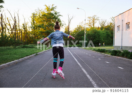 Girl riding roller skates in the park 91604115