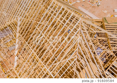 Timber frame beam framework house under construction with wooden trusses aerial view Timber frame beam framework house under construction with wooden trusses aerial view 91609584