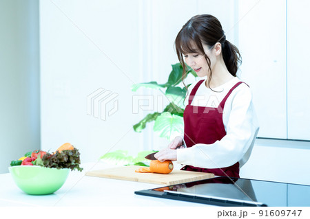 キッチンで料理をするエプロン姿の女性 キッチンで料理をするエプロン姿の女性 91609747
