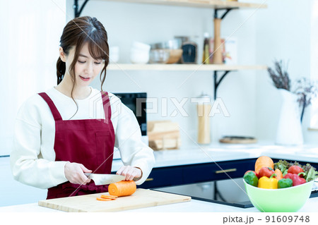 キッチンで料理をするエプロン姿の女性 キッチンで料理をするエプロン姿の女性 91609748