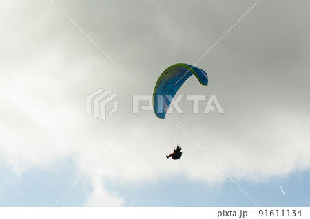 Paraglider flying over clouds in summer day Paraglider flying over clouds in summer day 91611134