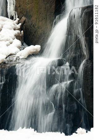 A small active waterfall. Clean mountain stream, snowy winter landscape, wildlife background 91611182