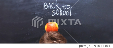 an apple on a child's head near chalkboard. Back to school concept background an apple on a child's head near chalkboard. Back to school concept background 91611304