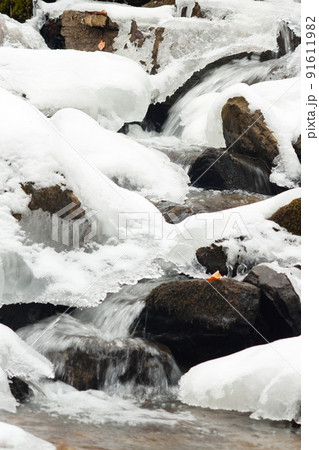 A small active waterfall. Clean mountain stream, snowy winter landscape, wildlife background 91611982