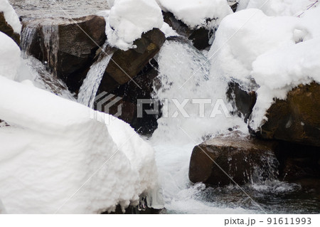 A small active waterfall. Clean mountain stream, snowy winter landscape, wildlife background 91611993