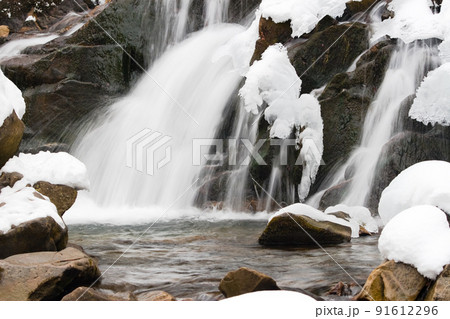 A small active waterfall. Clean mountain stream, snowy winter landscape, wildlife background 91612296