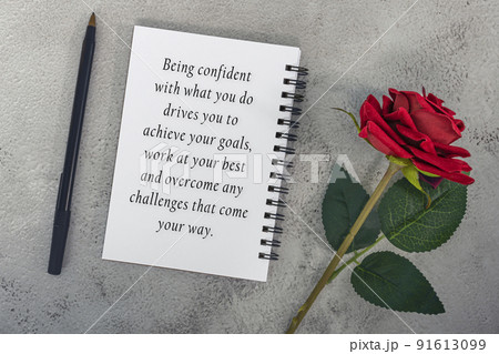 Motivational quote on note book with red roses and a pen. Motivational quote on note book with red roses and a pen. 91613099