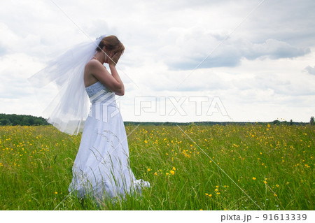 wedding day, beauty, nature concept. in the middle of the field there is an amazing woman wearing white bride dress, she is spinning around herself and sequins are shining in the light of sun 91613339