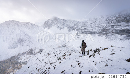 Hiker descending from the mountain during winter, narrow shot, Kananaskis, Canada 91614732