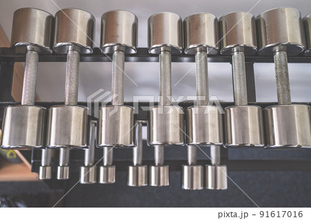 Iron dumbbells on a rack in fitness gym. Sport equipment, simulators. Background. 91617016