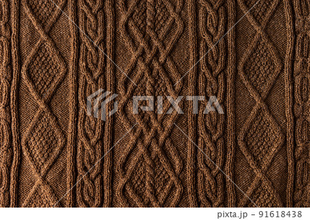 Knitted brown background. Large knitted fabric with a pattern. Close-up of a knitted blanket 91618438