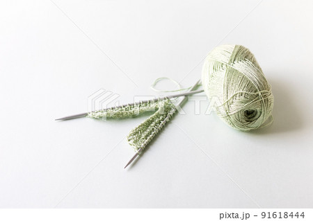 Green yarn thread with knitting needles on a green background for knitting. 91618444