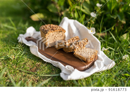 homemade grey bread with seeds on the wood board with the white cloth napkin on the green grass. High quality photo 91618773