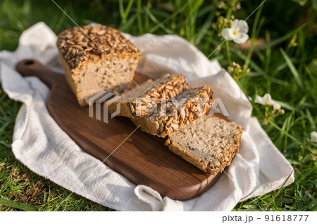 homemade grey bread with seeds on the wood board with the white cloth napkin on the green grass. High quality photo 91618777