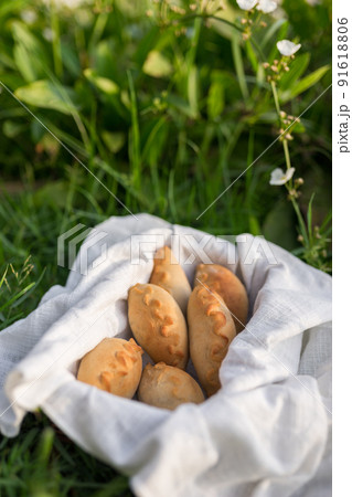 Composition of white flour buns in basket with white white cloth napkin on the green grass. High quality photo 91618806