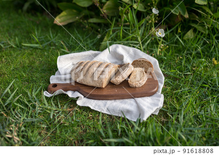 Composition of homemade white flour bread on wood board with white cloth napkin on the green grass . High quality photo 91618808