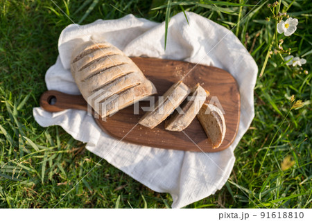Composition of homemade white flour bread on wood board with white cloth napkin on the green grass . High quality photo 91618810