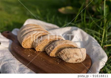 Composition of homemade white flour bread on wood board with white cloth napkin on the green grass . High quality photo 91618811