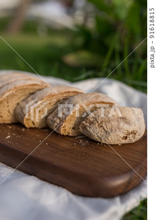 Composition of homemade white flour bread on wood board with white cloth napkin on the green grass . High quality photo 91618815