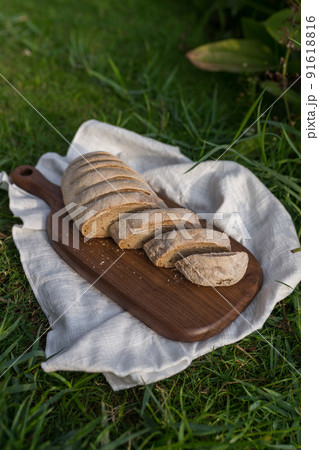 Composition of homemade white flour bread on wood board with white cloth napkin on the green grass . High quality photo 91618816