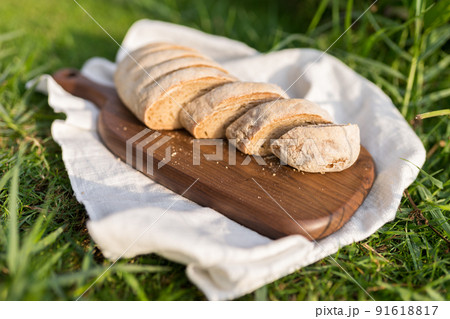 Composition of homemade white flour bread on wood board with white cloth napkin on the green grass . High quality photo 91618817