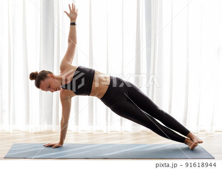Young woman doing her morning yoga routine at home near the big window Young woman doing her morning yoga routine at home near the big window 91618944