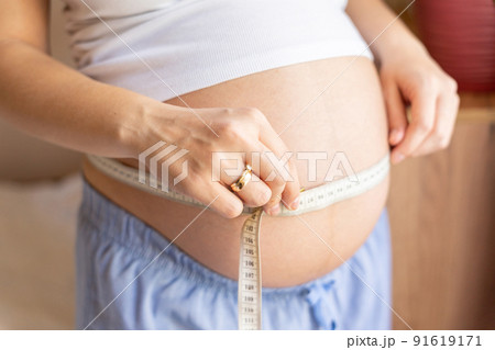 Measure belly pregnancy woman. Happy young pregnant woman with tape measuring belly. Concept maternity, pregnancy, childbirth. 91619171