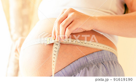 Measure body pregnancy woman. Happy beautiful pregnant woman with tape measuring belly. Concept of pregnancy, maternity, expectation for baby birth. 91619190