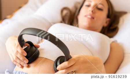 Pregnancy music woman listen. Pregnant woman listening to music. Mother belly listen headphones sound. Concept of pregnancy, maternity, expectation for baby birth. 91619239