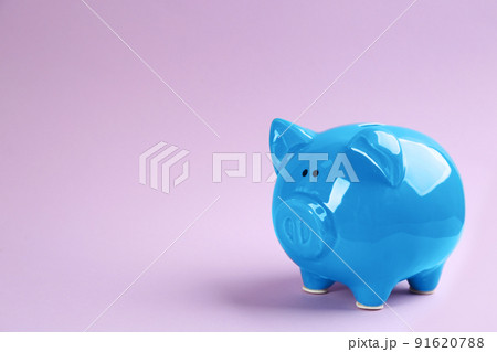 Blue piggy bank on violet background. Space for text Blue piggy bank on violet background. Space for text 91620788