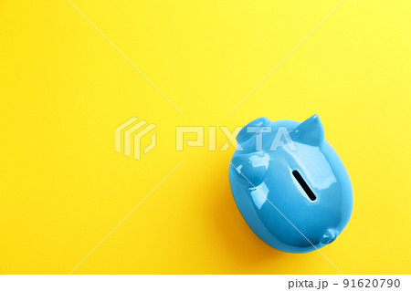 Blue piggy bank on yellow background, top view. Space for text 91620790
