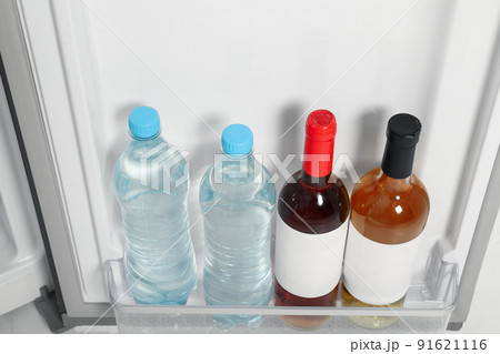 Bottles of water and wine on shelf in refrigerator Bottles of water and wine on shelf in refrigerator 91621116