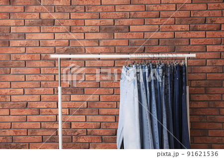 Rack with stylish jeans near brick wall Rack with stylish jeans near brick wall 91621536