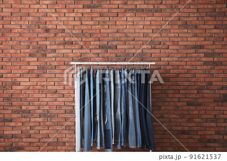 Rack with stylish jeans near brick wall Rack with stylish jeans near brick wall 91621537