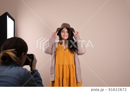 Photographer taking picture of overweight woman on beige background. Plus size model Photographer taking picture of overweight woman on beige background. Plus size model 91622672