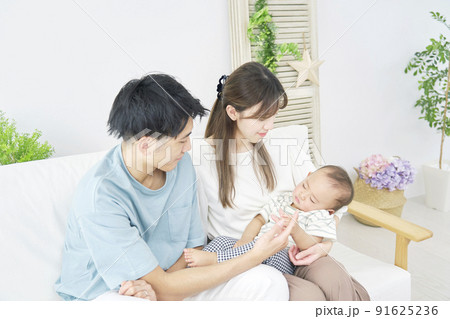 リビングで昼寝する赤ちゃんを見る両親 リビングで昼寝する赤ちゃんを見る両親 91625236