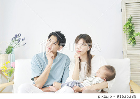 リビングで赤ちゃんを抱っこして考える両親 91625239